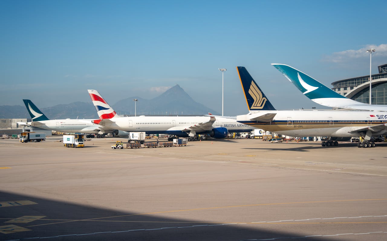 Multiple commercial airplanes parked at an airport terminal with a mountain view in the background.